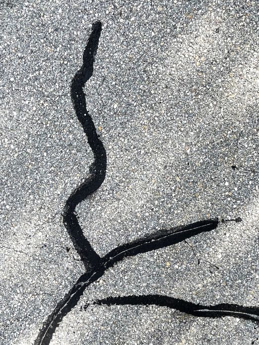 Nahaufnahme mit Teer ausgebesserten Risse in der Strasse, aufgenommen von Thomas Pfister