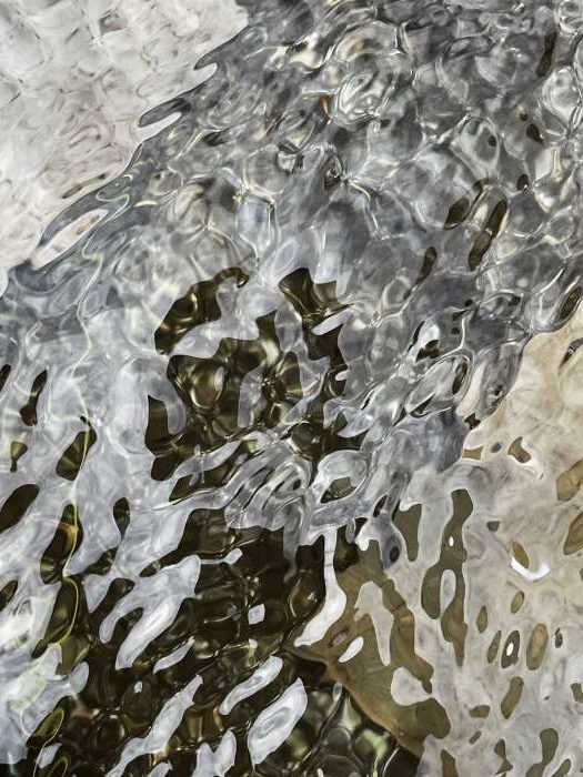 Nahaufnahme in wassergefüllten Steintrog mit Urnenplaquetten, Fotografie Thomas Pfister